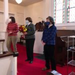 Three members of the choir listen as Chris Psolka is regaled for her music ministry at Christ Church